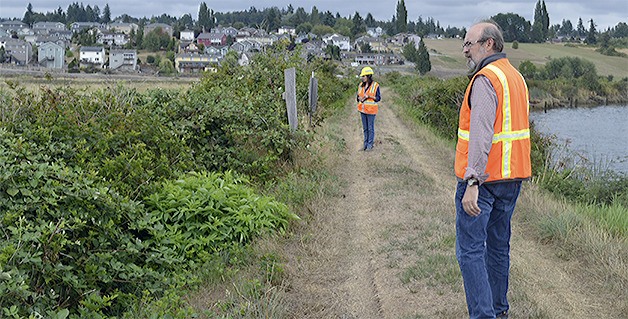 Project manager Kurt Nelson and communications director Francesca Hillery walk along the part of the old levee that will be breached so a mixture of fresh and salt water from Ebey Slough at right can flow to the left into the restored Qwuloolt estuary.