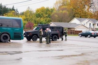 Law enforcement personnel confer during a Oct. 17 standoff near the Shoultes neighborhood. Two local schools were locked down for hours after a bank was robbed in the early morning hours and the 17-year-old suspect fled to his house in the 10600 block of 52nd Avenue NE.