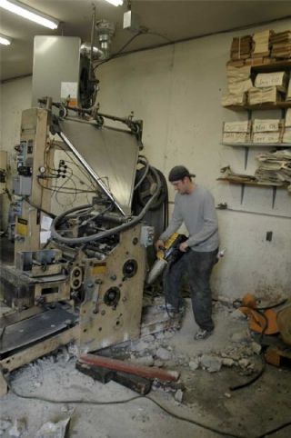 Payson West of ImPRESSions Worldwide applies a jackhammer to the base of the press in The Globe offices.