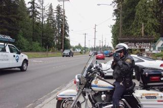 Marysville Police officer Dale Coleman keeps an eye on State Avenue traffic earlier this week.  Officers are using a new tool to bust red-light runners that helps keep themselves safe at the same time. Bright blue LEDs on the back of traffic signals are synchronized with red lights so police can monitor traffic infractions from several blocks away. It helps us get in position