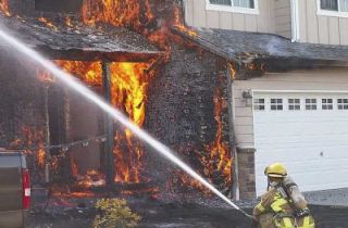 An unidentified firefighter helps take on the blaze that engulfed a home in the 3800 block of 64th Avenue.