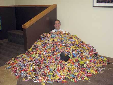 Marysville orthodontist Dr. Jason Bourne buries himself in last year's collection of more than 735 pounds of Halloween candy.