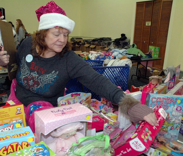 Marysville holiday toy store volunteer Christina Leslie examines a girls’ tea set during distributions to needy families on Dec. 18.