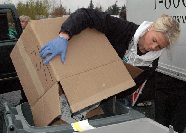 Arlington High School Class of 2012 graduate Makenzie Milless helps load the bins for the Community Shred-A-Thon on April 20.