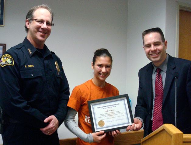 Mayor Jon Nehring and Police Chief Rick Smith present Play it Again Sports employee Brie Stewart with a certificate of commendation for foiling a bike theft at their Marysville store on Feb. 17