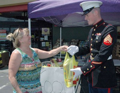 Marysville Grocery Outlet shopper Kay Kynaston donates a bag of food to Marine Corps Sgt. Randall Murphy during Toys for Tots’ June 29 collection drive.