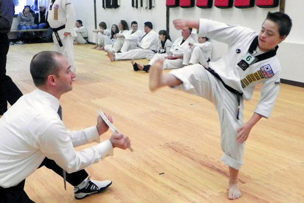 Scotty Grossman prepares to break a board held by Master Thad Ekle at Marysville’s U.S. Taekwondo Academy during one of Grossman’s two second-degree blackbelt tests.