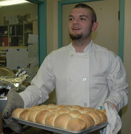 Jordan Anderson takes a tray of piping-hot rolls fresh out of the oven at the School House Cafe on Jan. 5.