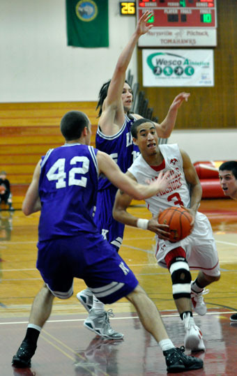 Marysville-Pilchuck senior guard Dominique Kiblinger takes the ball to the paint against Kamiak senior post J.D. Blacksmith as Knights senior guard Nicholas Kussman leaps to block the layup.