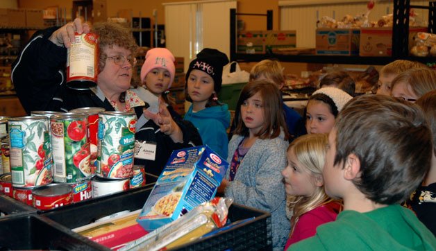 Marysville Community Food Bank volunteer Alonna Chatburn explains to third-grade students from the Marysville Cooperative Education Program how many portions of each type of food are allowed for the food bank’s customers