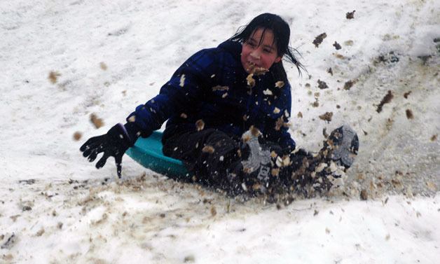 Angelica Rodriguez crashes into the slope of the small ramp at the foot of one of the snow-covered hills in Jennings Park on Jan. 20.