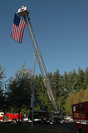 The Marysville Fire District's ladder truck hoists the American flag high over the Police and Firefighters' Memorial in front of the Marysville Library on Sept. 11