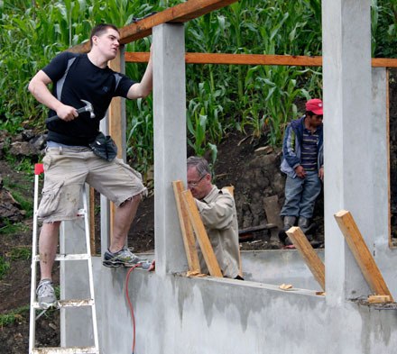 Drew Culver balances on a ladder to check the frame of the two-room school that he and his fellow Rotarians are building in Vuelta Grande