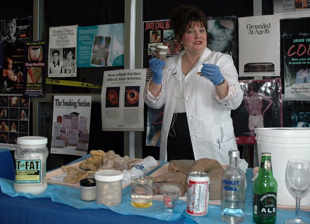 Arlington-based registered nurse and “Organ Lady” Kathy Ketchum holds up a container full of gallstones during “InsideOut: The Original Organ Show” at the Providence Regional Medical Center in Everett on Feb. 25.