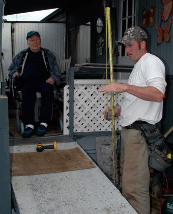 Marysville’s Anguess Adkins looks on as Master Builders Care Foundation volunteer Andy Gemmer plans to install new support columns for Adkins’ wheelchair ramp on May 14.